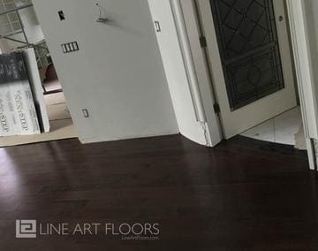 Dark hardwood flooring in a modern, empty room with white walls.