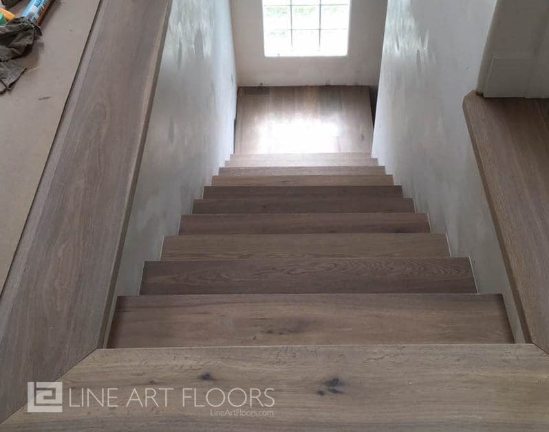 Top view of wooden stairs with natural light from a window.