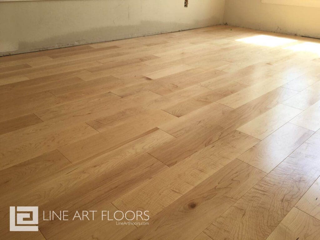 Light wooden floor with natural grain patterns in a bright room.