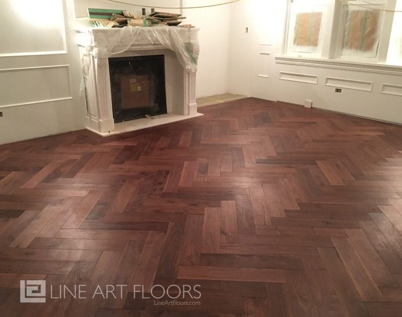 Elegant herringbone wood flooring in a bright room with a white fireplace.